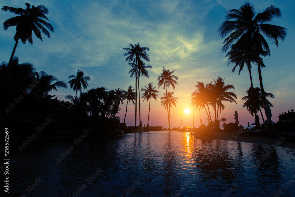 Beautiful twilight on tropical beach with silhouettes of palm trees.
