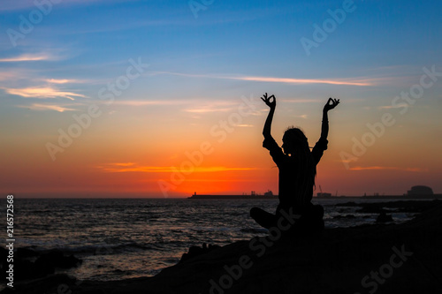 Yoga meditation woman silhouette during amazing sunset on the ocean. Fitness and healthy.