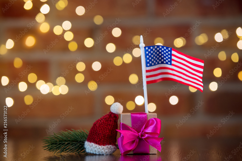handmade gift box with purple bow and USA flag on wooden table with fairy lights on bokeh background