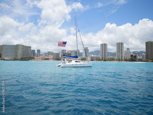 a sail boat with american flag in front of Waikiki beach Honolulu Hawaii