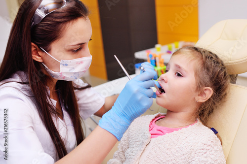 The dentist examines a child s teeth in a dental chair.