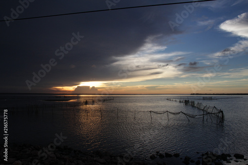 Foto Sonnenuntergang mit dramatischem Himmel und Fischernetzen