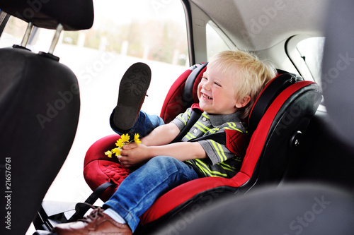 portrait of a young child of a boy with blond hair in a children's car seat. Safe transportation of children in the car.