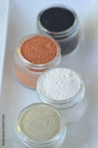 Top view of kaolin powder, activated charcoal, red, green and green cosmetic clays in jars. Deep cleansing bentonite (montmorillonite) clay for beauty spa face mask, body detox and hair treatments. 