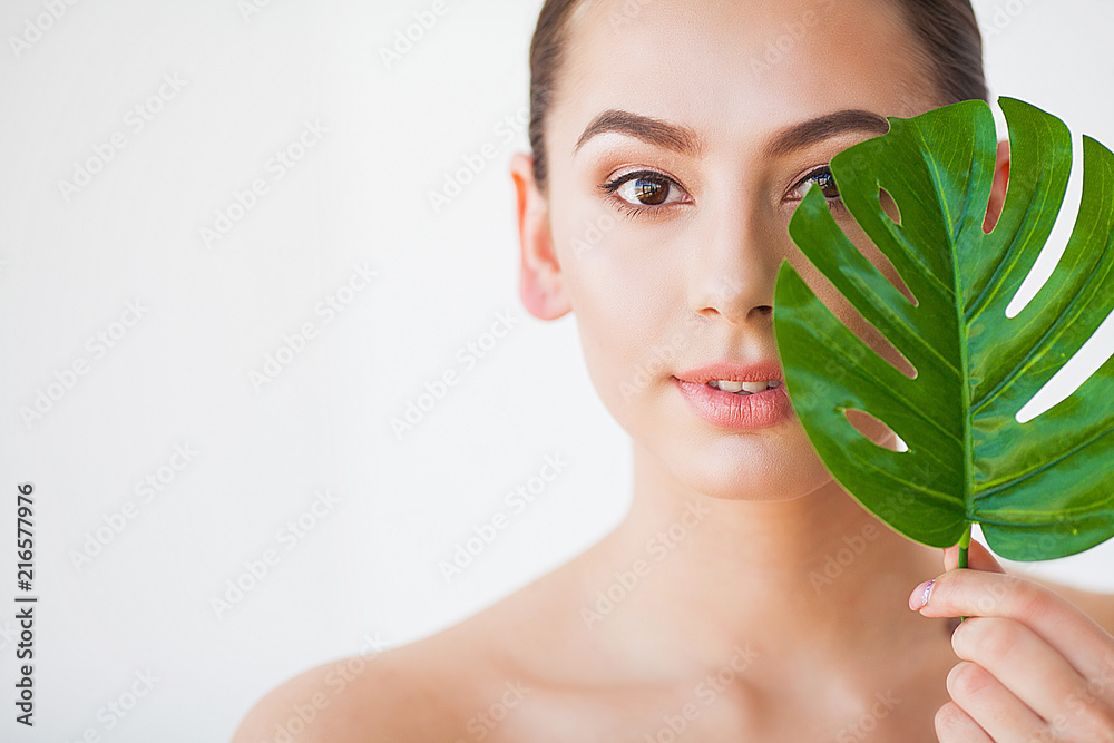 Skincare. Beautiful Woman Portrait on White Background With Clean Skin and Green Leaf in Hand Skincare. Beautiful Woman Portrait on White Background With Clean Skin and Green Leaf in Hand