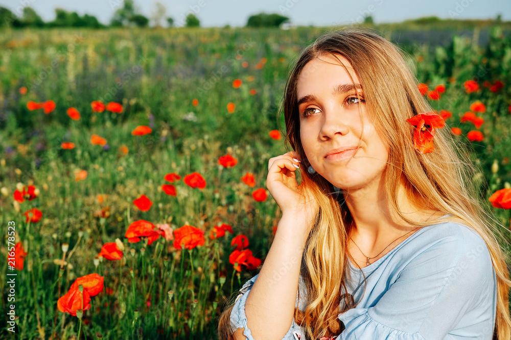 Happy young blond woman smiling in the field of poppies Happy young blond woman smiling in the field of poppies