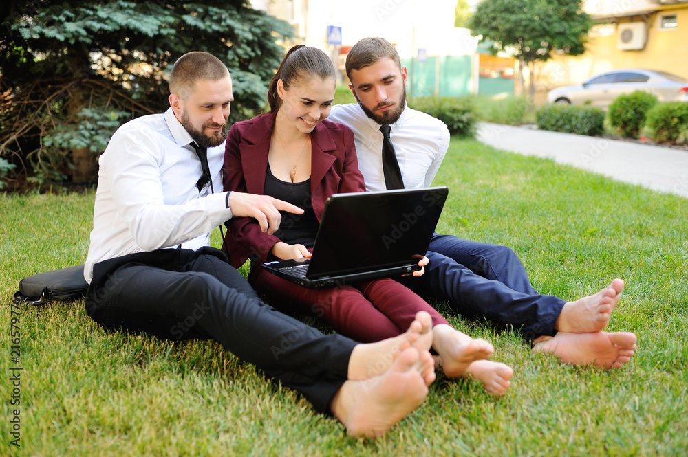 Fotka „office workers in business clothes sitting barefoot on the grass.  Lunch break, yoga, relaxation“ ze služby Stock | Adobe Stock