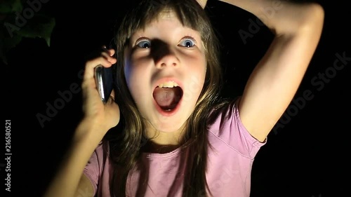 frightened little girl, screaming and calling for help, trying to get through the phone to parents. the child was lost at night in the forest