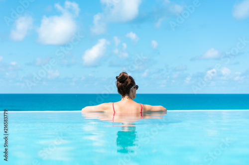 Woman relaxing on vacation in infinity edge swimming pool