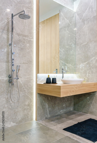 Spacious and bright modern bathroom interior with white walls, a shower cabin with glass wall, a toilet and faucet sink