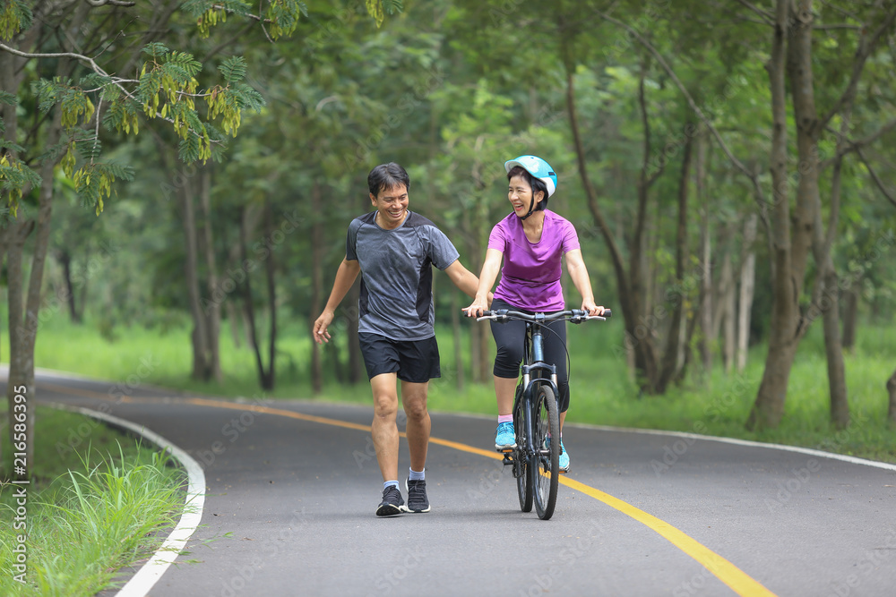 Fototapeta premium Middle aged couple walking with their bicycle in park