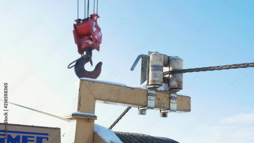 steel wire rope moves between cable guide rollers on support by crane