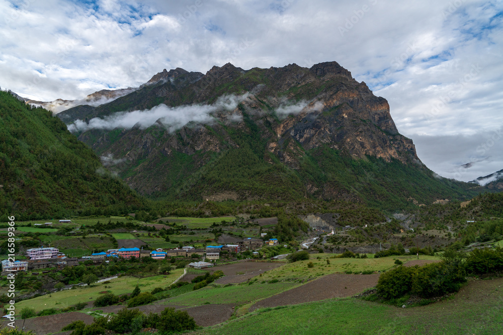 A foothill mountain stands out in the clouds above Lower Pisang