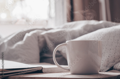 Breakfast in bed, a tray of tea, croissants, fruit, flowers. Open the book the text is out of focus. Background layout. a day off