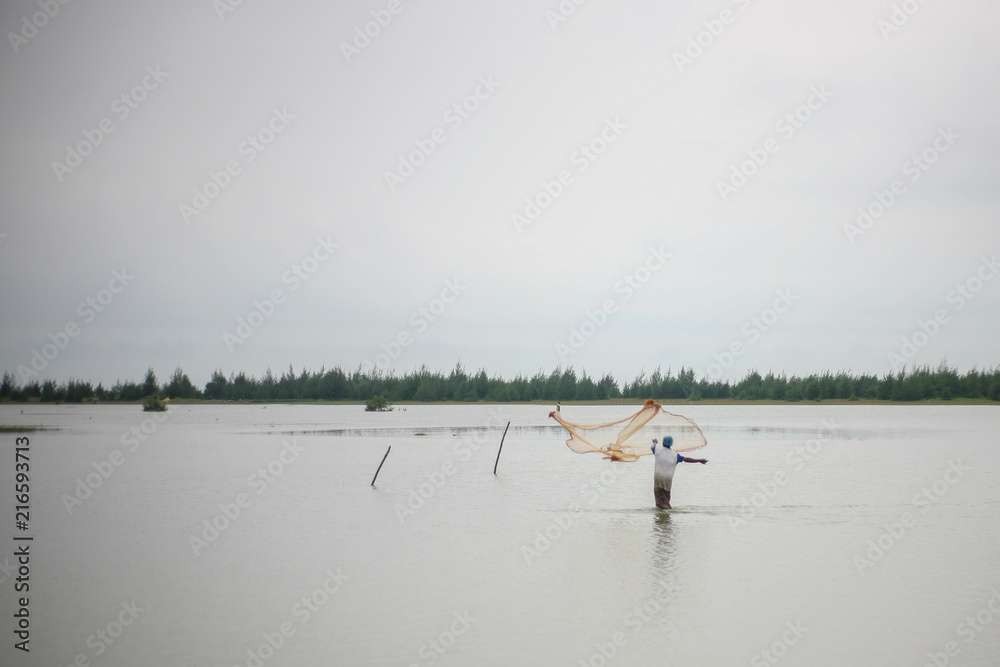 Fisherman Fishing with a fishing net on the beach in Cox's Bazar Bangladesh during sunset