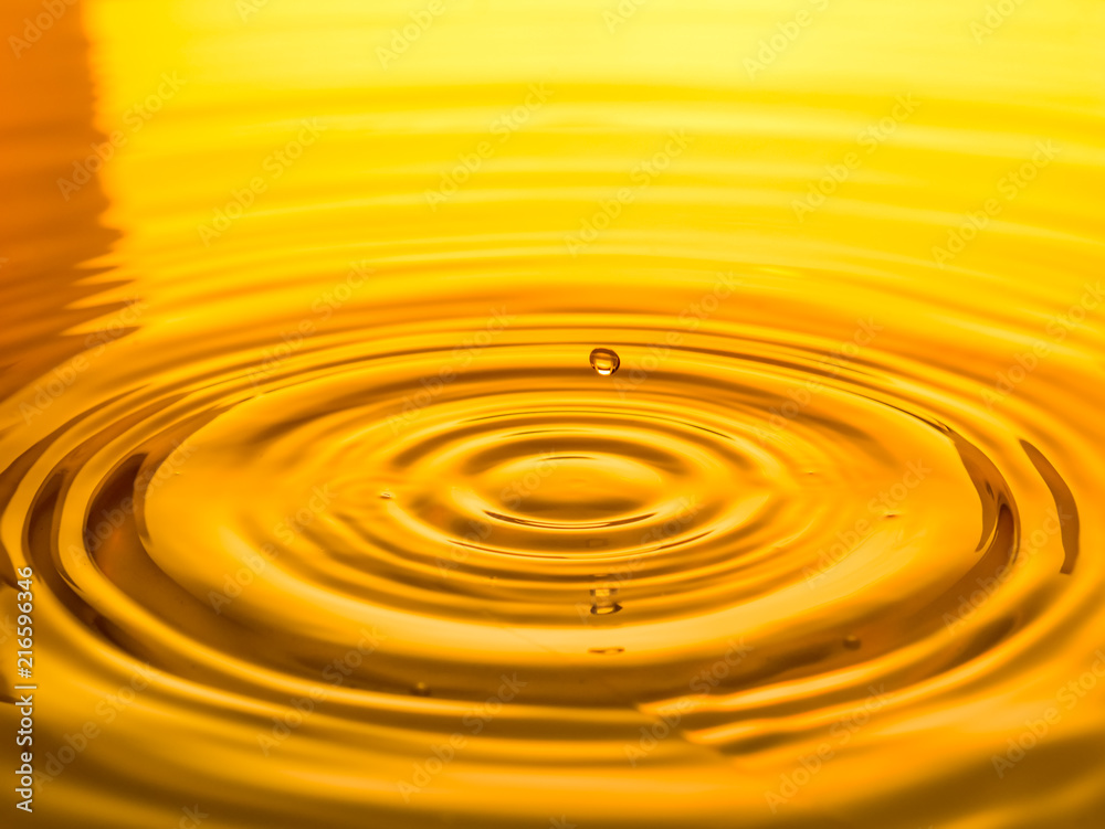 close up of a drop oil on a yellow background close up of a drop oil on a yellow background