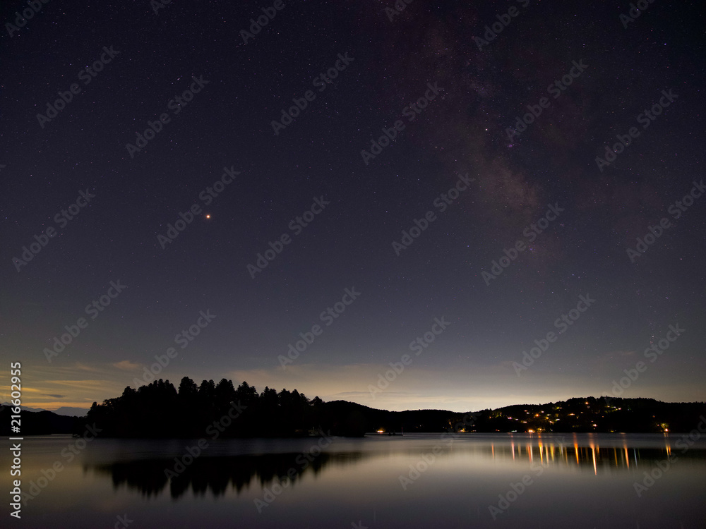 夜の湖畔にて、島の真上に火星、隣に天の河、街灯りが湖面に輝く。