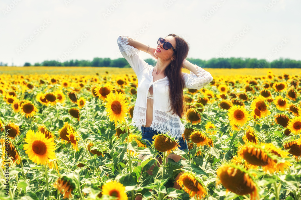 Fototapeta premium Beautiful young girl outdoors . A young girl is having fun in the field with flowering sunflowers .