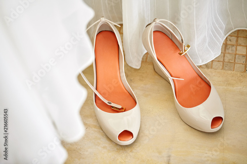 Beautiful women's nude pump shoes with orange-red insoles, top-view with part of white cloth blurry in foreground