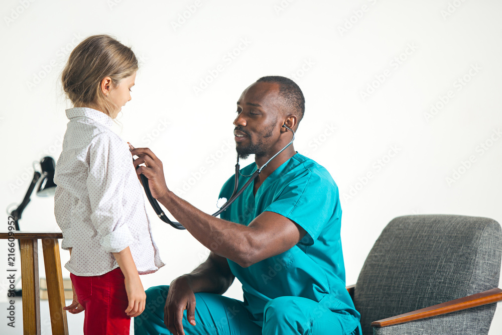 Fototapeta premium The healthcare and medical concept - african male doctor with stethoscope listening to child chest in hospital. The doctor, health, medicine, patient, pediatrician, illness concepts