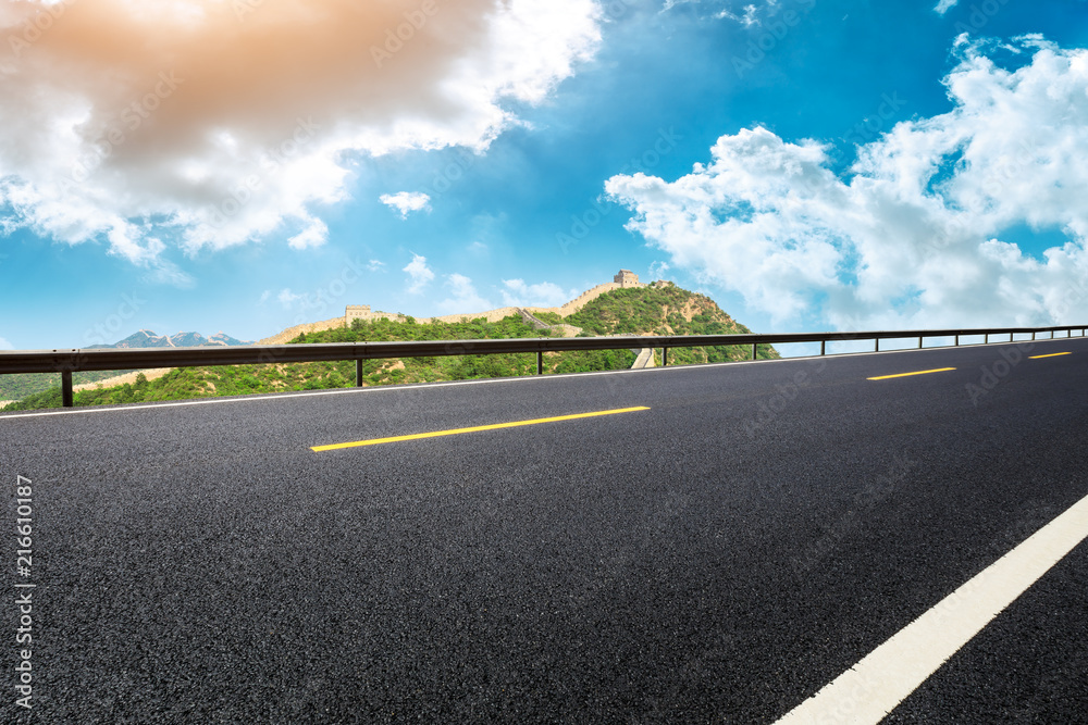 Fototapeta premium Empty asphalt road and great wall with mountains under the blue sky