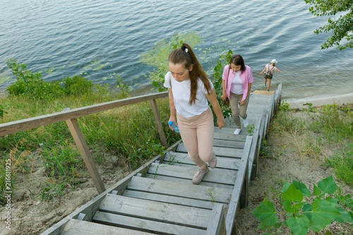 People walk up the wooden staircase. Background river, nature, summer. © Valerii Honcharuk