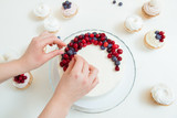 Woman decorating a delicious cake with blueberries