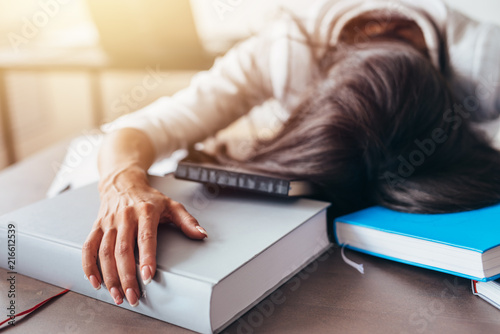 Portrait of tired and tortured female student sleeping on the table