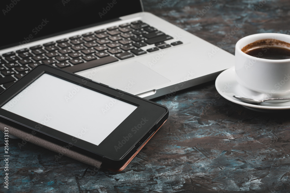 E-book and paper books on the table with a cup of coffee, a laptop and reading glasses. Concepts of self-education. E-book and paper books on the table with a cup of coffee, a laptop and reading glasses. Concepts of self-education.