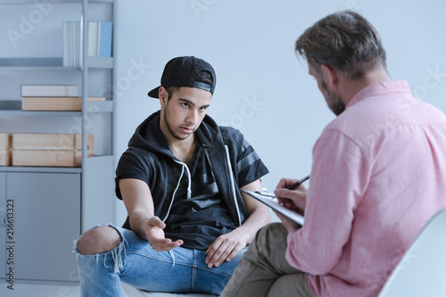 Fototapet Rebellious juvenile boy in trouble explaining his behavior and a curator taking