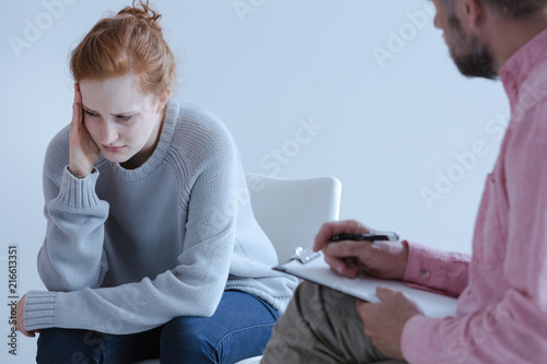 Obraz na płótnie Young woman with emotional problems thinking about the future and talking to a psychologist during an individual therapy meeting