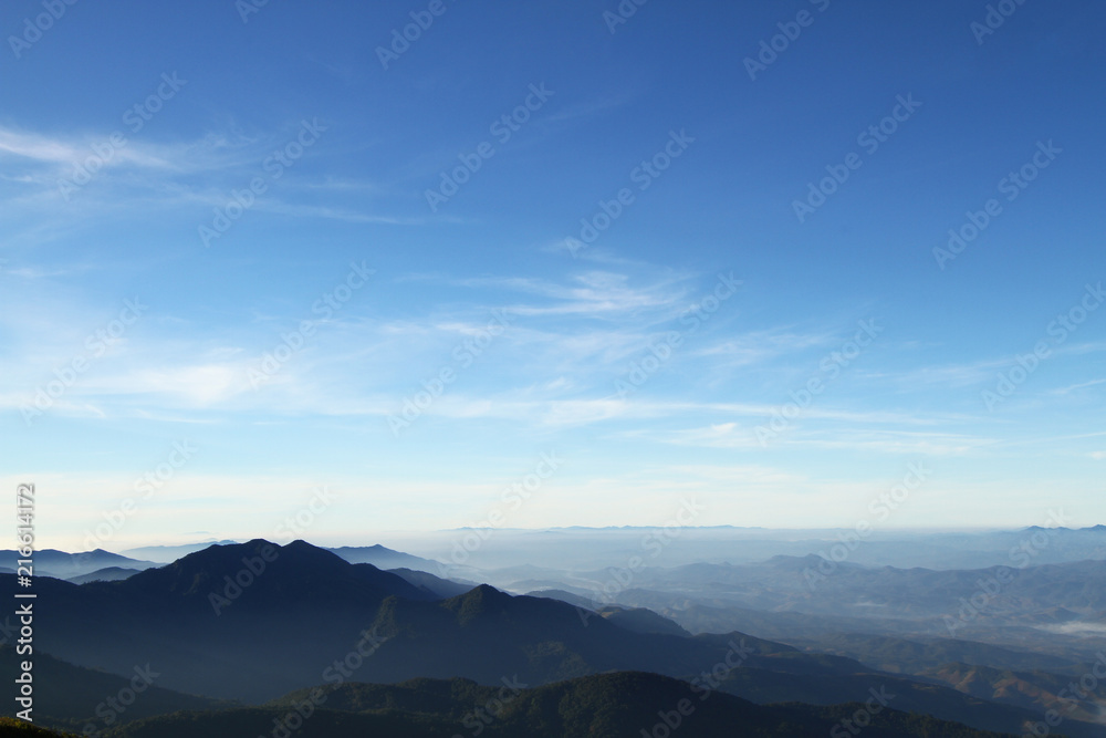 Beautiful layers of mountain range landscape with winter blue sky from top view in majestic sunrise and fog