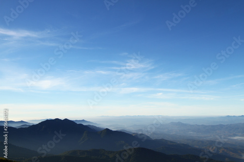 Beautiful layers of mountain range landscape with winter blue sky from top view in majestic sunrise and fog © iHaMoo