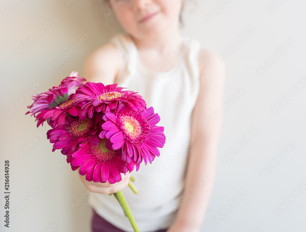 cropped view of child holding out a bunch of bright pink gerbera daisies (selective focus)