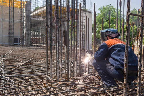construction worker welding metal rebar for the pouring of foundation. candid, real people