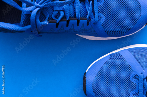 Blue sport sneakers for running on the blue background with copy space.