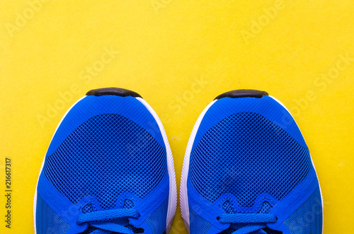 Blue sneakers on the yellow background. Sport footwear flatlay.