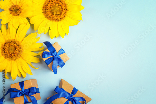 Fototapeta Naklejka Na Ścianę i Meble -  Blue background with a yellow sunflowers and gift boxes with blue ribbons