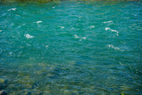turquoise river water with small waves and stones