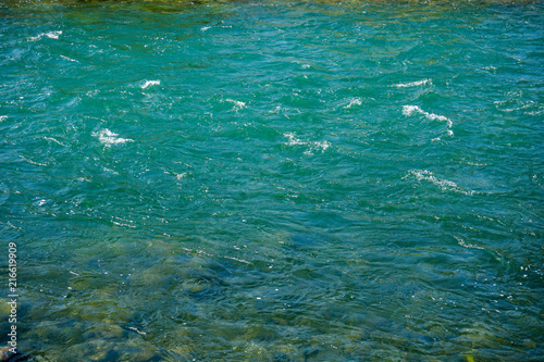 turquoise river water with small waves and stones