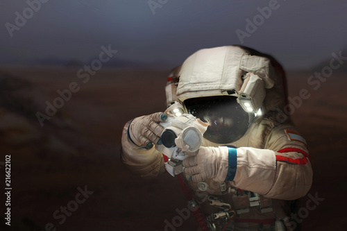 Spaceman with a camera in a space suit on the planet Mars. Astronaut takes pictures a new planet.