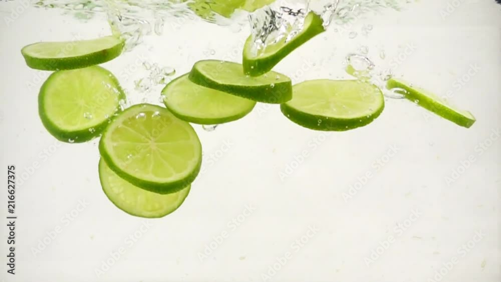Round lime slices slowly sink in water, slow motion close-up Round lime slices slowly sink in water, slow motion close-up