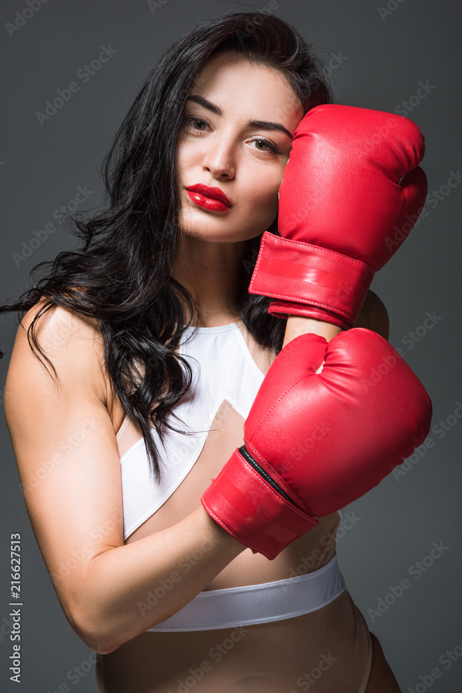 sexy sportive woman in white sportswear showing boxing gloves isolated on grey sexy sportive woman in white sportswear showing boxing gloves isolated on grey