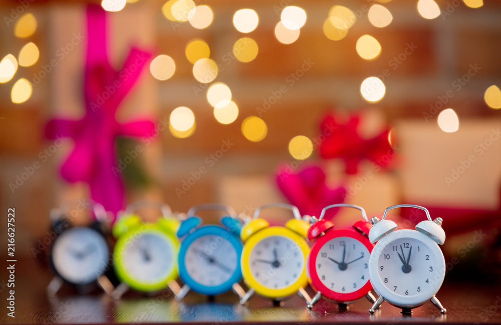 group of alarm clocks on background with fairy lights and gifts in bokeh. Christmas Holiday season