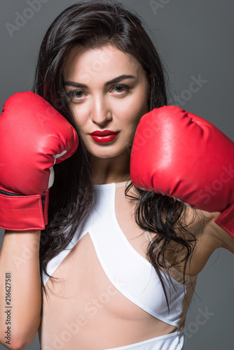 portrait of attractive boxer in white swimwear and boxing gloves isolated on grey © LIGHTFIELD STUDIOS