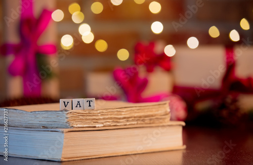 VAT word and books on background with fairy lights and gifts in bokeh. Christmas Holiday season