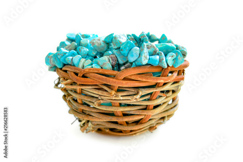 Pile stones of raw Turquoise in small wooden nest on a white background