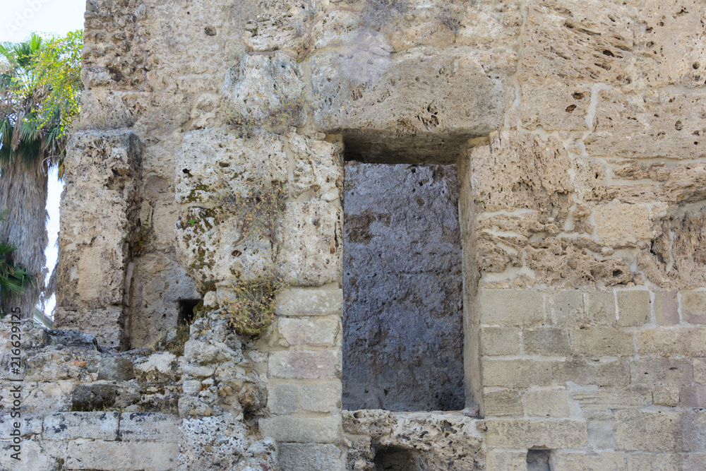 the stone wall of the ancient limestone building with a doorway. Side, Turkey