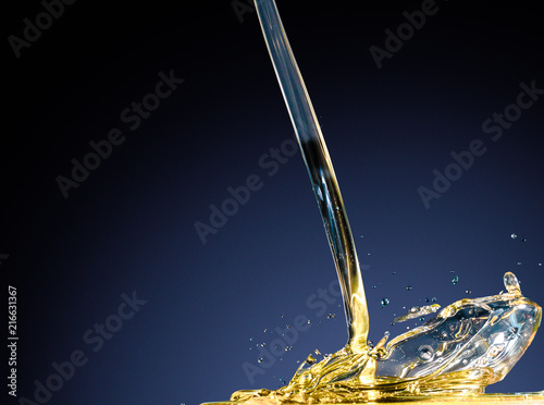 Close-up of oil and liquid pouring on dark blue background. Isolated studio shooting