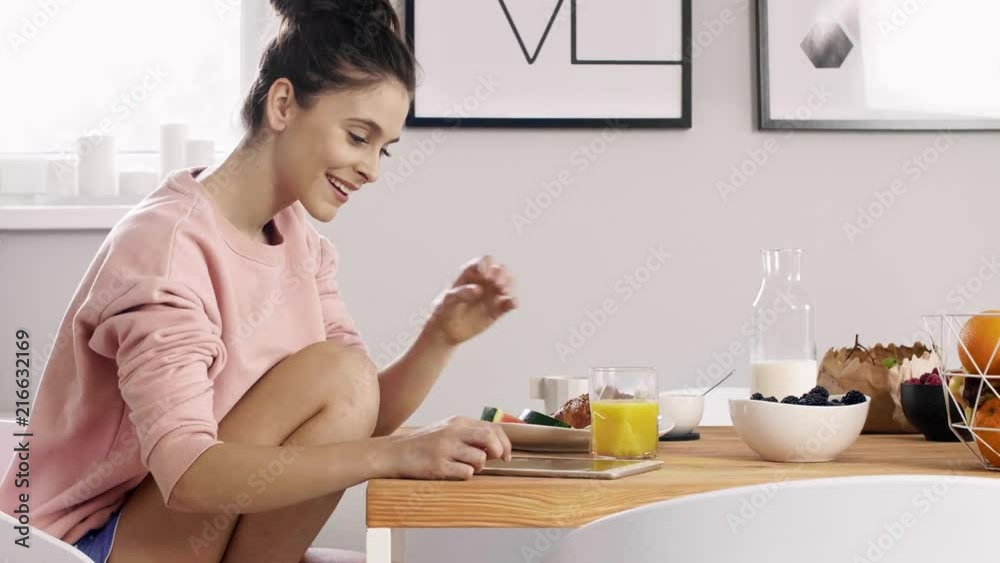 Young woman using a tablet and drinking orange juice Young woman using a tablet and drinking orange juice